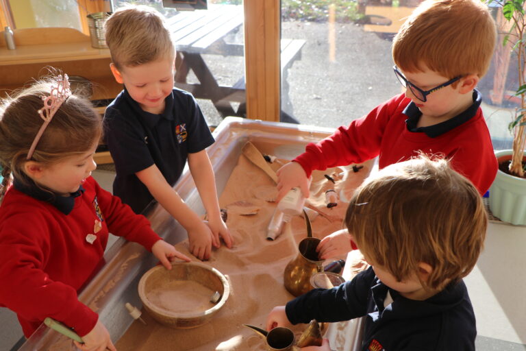 Nursery pupils playing together in class at the sand pit.