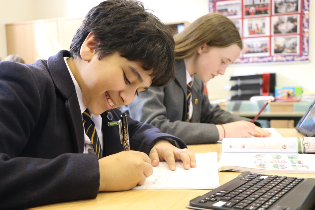 Modern Languages. Pupils at desks working and writing looking cheerful.
