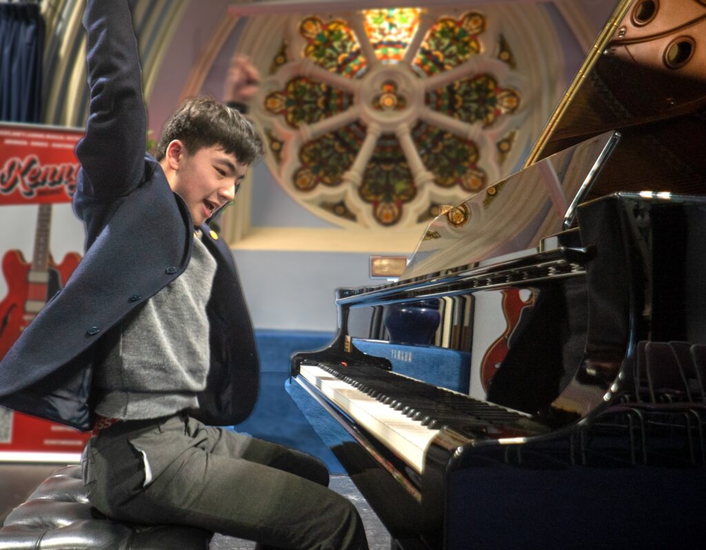 Snr pupil is delighted to be playing piano in Trinity with arms in the air
